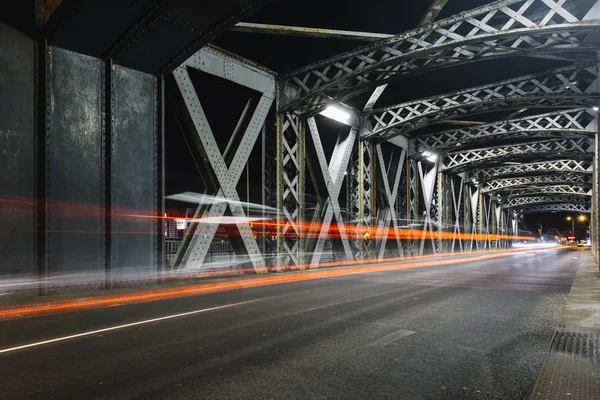 Şehirde bir köprünün çelik konstrüksiyon altında asfalt yol. Gece araba tünelde ışık yollar ile kentsel sahne. Tonda