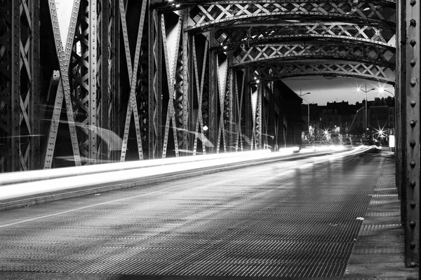 Şehirde bir köprünün çelik konstrüksiyon altında asfalt yol. Gece araba tünelde ışık yollar ile kentsel sahne. Siyah ve beyaz