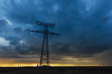 Yüksek gerilim enerji hatları ve enerji nakil direkleri gün batımında. Polonyalılar ve genel gider güç hatları siluetleri dusk içinde. Elektrik üretim ve dağıtım. Elektrik Sanayi ve doğa kavramı
