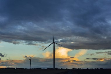 Rüzgar türbinleri Normandy, Fransa için bulutlu bir günde yeşil alanlardaki elektrik enerjisi üretimi için. Yenilenebilir enerji kaynakları, endüstriyel tarım kavramı. Çevre dostu enerji üretim