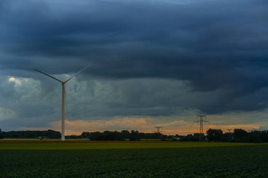 Elektrik enerjisi üretimi ve yeşil alan güç hatları için bulutlu gün Normandy, Fransa Rüzgar jeneratörler. Yenilenebilir enerji kaynakları, endüstriyel tarım kavramı. Çevre dostu enerji üretim