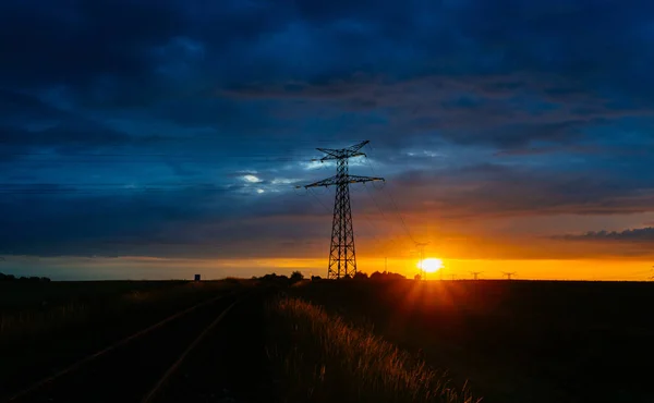 Linie wysokiego napięcia i wież transmisyjnych o zachodzie słońca. Polacy i napowietrznych linii sylwetki w zmierzchu. Wytwarzanie energii elektrycznej i dystrybucji. Koncepcja przemysłu i charakter energii elektrycznej — Zdjęcie stockowe