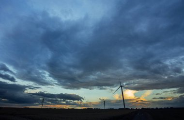 Bulutlu gün tarım alanında Normandy, Fransa için rüzgar türbini elektrik enerjisi üretimi için. Yenilenebilir enerji kaynakları, endüstriyel tarım kavramı. Çevre dostu enerji üretim