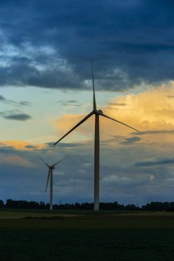 Bulutlu gün tarım alanında Normandy, Fransa için rüzgar türbini elektrik enerjisi üretimi için. Yenilenebilir enerji kaynakları, endüstriyel tarım kavramı. Çevre dostu enerji üretim