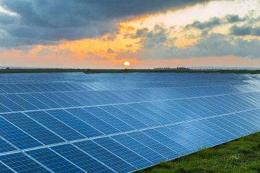 Normandy, Fransa için bulutlu gökyüzü ile gündoğumu, güneş panelleri. Güneş enerjisi, modern elektrik enerjisi üretim teknolojisi, yenilenebilir enerji kavramı. Çevre dostu elektrik üretimi