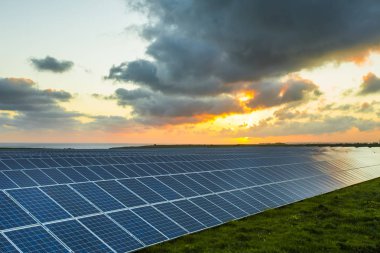 Normandy, Fransa için bulutlu gökyüzü ile gündoğumu, güneş panelleri. Güneş enerjisi, modern elektrik enerjisi üretim teknolojisi, yenilenebilir enerji kavramı. Çevre dostu elektrik üretimi