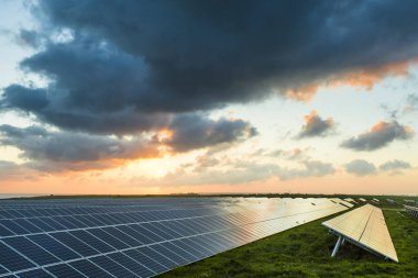 Normandy, Fransa için bulutlu gökyüzü ile gündoğumu, güneş panelleri. Güneş enerjisi, modern elektrik enerjisi üretim teknolojisi, yenilenebilir enerji kavramı. Çevre dostu elektrik üretimi