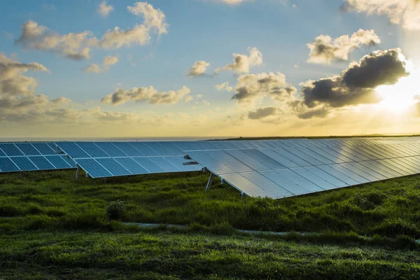 Solar panels at sunrise with dramatic cloudy sky in Normandy, France. Modern electric power production technology. Environmentally friendly electricity production — Stock Photo, Image