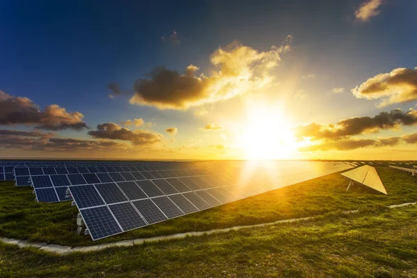 Solar panels at sunrise with cloudy sky and sunbeams in Normandy, France. Solar energy, technology of electricity generation, renewable energy sources concept. Environment friendly energy production — Stock Photo, Image