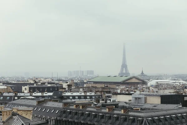 O horizonte de Paris com telhados e a torre Eiffel em um dia nebuloso. Símbolo de Paris e marco icónico. Lugares turísticos famosos e destinos de viagem românticos na Europa. Conceito de turismo — Fotografia de Stock