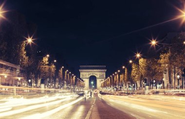 Işıklı Arc de Triomphe ve avenue Champs-Elysees Paris. Ünlü turistik yerlere ve ulaşım kavramı. Sokak trafik ve şehir ışıkları ile gece kentsel peyzaj. Uzun pozlama. Tonda