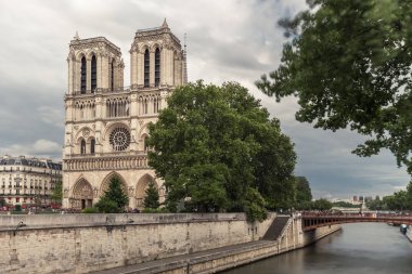 Notre-Dame de Paris, bulutlu bir günde Seine Nehri iskele üzerinde ünlü antik Katolik Katedrali. Fransa'nın turistik tarihi ve mimari landmark. Din, turizm ve seyahat kavramı.