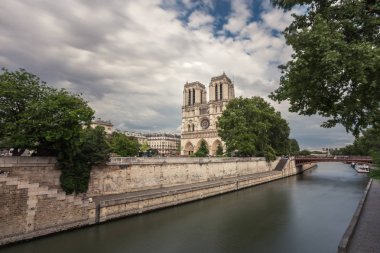 Notre-Dame de Paris, bulutlu bir günde Seine Nehri iskele üzerinde ünlü antik Katolik Katedrali. Fransa'nın turistik tarihi ve mimari landmark. Din, turizm ve seyahat kavramı.