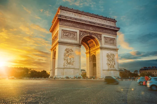 Famous Paris avenue Champs-Elysees and the Triumphal Arch, symbol of the glory on sunny day with sunbeams in sky. Iconic touristic landmark and romantic travel destinations in France. Long exposure — Stock Photo, Image