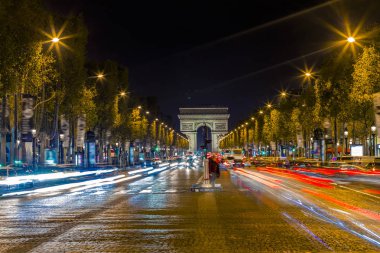 Işıklı Arc de Triomphe ve avenue Champs-Elysees Paris. Ünlü turistik yerlere ve ulaşım kavramı. Sokak trafik ve şehir ışıkları ile gece kentsel peyzaj. Uzun pozlama. Tonda