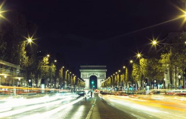 Işıklı Arc de Triomphe ve avenue Champs-Elysees Paris. Ünlü turistik yerlere ve ulaşım kavramı. Sokak trafik ve şehir ışıkları ile gece kentsel peyzaj. Uzun pozlama. Tonda