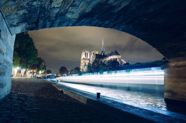 Notre-Dame de Paris gece. Seine Nehri ve şehir ışıkları yansıma iskele üzerinde ünlü antik Katolik Katedrali. Turistik tarihi ve mimari dönüm noktası. Turizm ve seyahat kavramı.