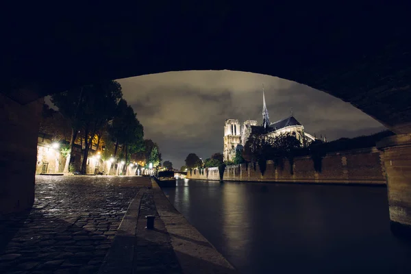 Notre-Dame de Paris de noche. Famosa catedral católica antigua en el muelle del río Sena y reflexión luces de la ciudad. Monumento histórico y arquitectónico turístico. Concepto de turismo y viajes . — Foto de Stock