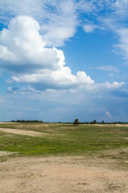 Çölde yeşil çim üzerinde gökyüzünde güzel bulutlar.