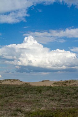 Çölde yeşil çim üzerinde gökyüzünde güzel bulutlar.