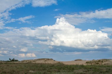 Çölde yeşil çim üzerinde gökyüzünde güzel bulutlar.