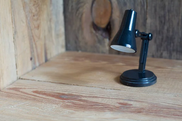 Невелика настільна лампа з чорного пластику на дерев'яному фоні . — стокове фото