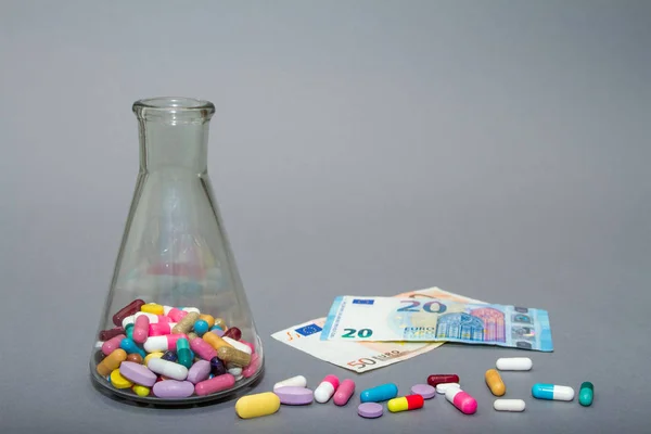 Píldoras médicas en diferentes colores y dinero . — Foto de Stock