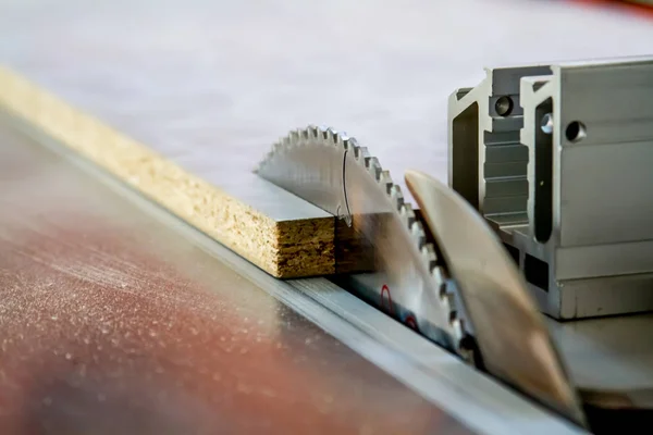 Los hombres trabajan aserrando madera. Sierra circular. Una máquina que sierra madera, tableros de partículas y tableros de fibra . — Foto de Stock