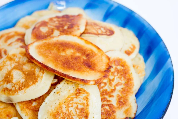 Rostige, frisch gekochte Pfannkuchen liegen auf einem blauen Teller auf weißem Hintergrund. — Stockfoto