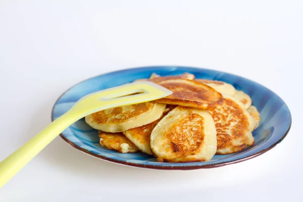 Rostige, frisch gekochte Pfannkuchen liegen auf einem blauen Teller auf weißem Hintergrund. — Stockfoto
