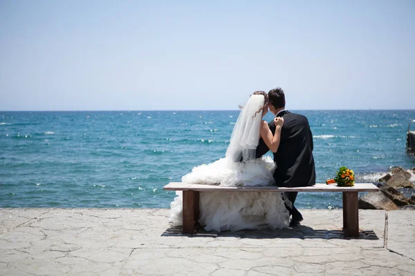 Çift gülümseyen ve düğün yakınındaki kucaklayan kumsalda arch. Deniz ya da okyanus balayı