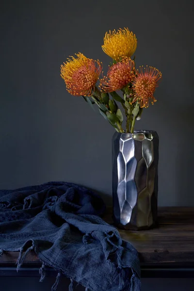 Ramo de flores de protea exóticas amarillas y anaranjadas en un jarrón de metal sobre un fondo oscuro, enfoque selectivo —  Fotos de Stock