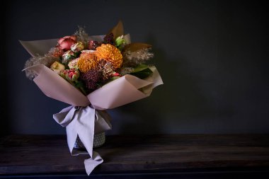 Koyu bir arka planda, seçici bir odak noktasında klasik tarzda dekore edilmiş cam bir vazoda yakın plan buketi.