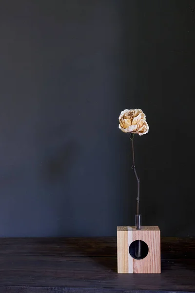 Piękna beżowa sucha róża w drewnianym wazonie na ciemnym tle, wybiórcza ostrość — Zdjęcie stockowe