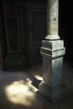 Mermer kare bir sütuna yakın çekim ve karanlık bir odada güneş ışığı, seçici bir odak