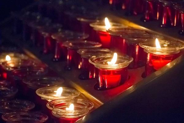 Close-up de um monte de velas vermelhas em uma igreja durante um serviço, foco seletivo — Fotografia de Stock