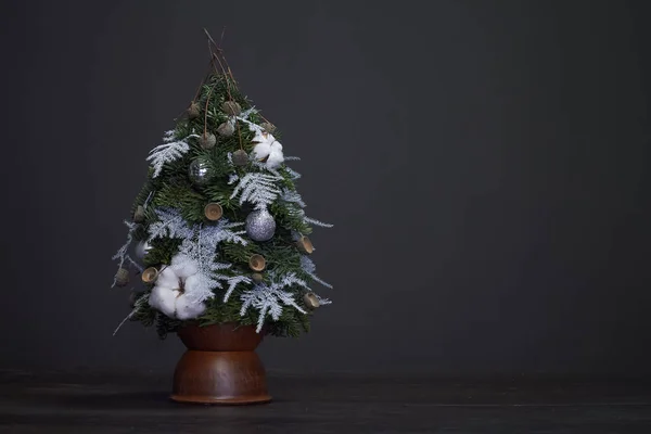 Christmas and New Year composition. Christmas tree made of fir branches and decorated by natural materials and balls in a clay pot — Stock Photo, Image