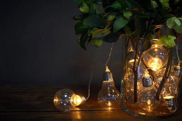 Glass vase filled with luminous bulbs and a bouquet of hellebore, festive concept — Stock Photo, Image