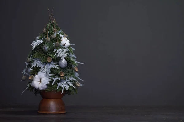 Composição de Natal e Ano Novo. Árvore de Natal feita de ramos de abeto e decorada por materiais naturais e bolas em um pote de barro — Fotografia de Stock