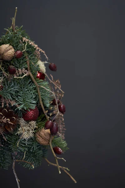 Jul- och nyårskomposition. Julgran gjord av gran grenar och dekorerad med naturliga material och bollar på mörk bakgrund — Stockfoto