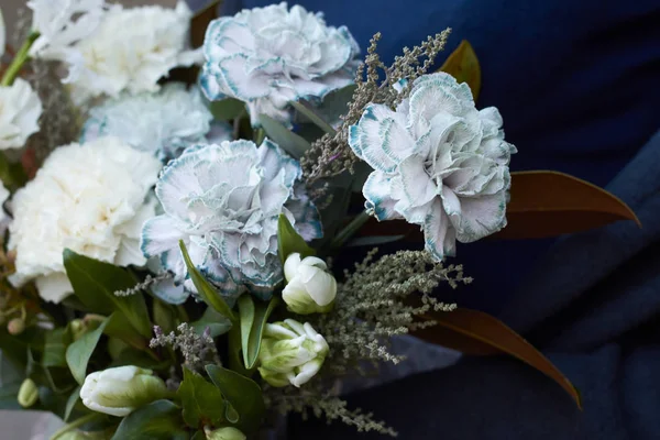 Close-up mãos femininas mantém bouquet tonificado branco em estilo vintage ao ar livre em um fundo de parede cinza, foco seletivo — Fotografia de Stock