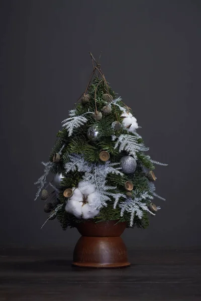 Jul- och nyårskomposition. Julgran gjord av gran grenar och dekorerad med naturliga material och bollar i en lerkruka — Stockfoto