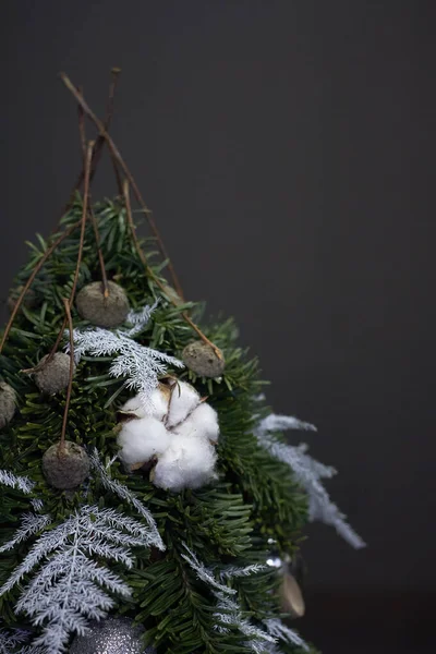 Weihnachts- und Neujahrskomposition. Detailaufnahme Weihnachtsbaum aus Tannenzweigen, dekoriert mit Naturmaterialien und Kugeln vor dunklem Hintergrund — Stockfoto