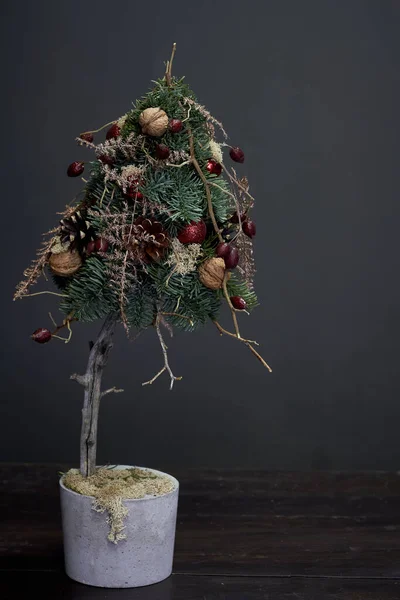 Jul- och nyårskomposition. Julgran gjord av gran grenar och dekorerad med naturliga material och bollar i en cementkruka — Stockfoto