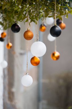 Yeni yıl ya da Noel arkaplanı, beyaz ve altın noel balolarına yakın çekim ve bulanık arka planda ökseotu, seçici odaklanma