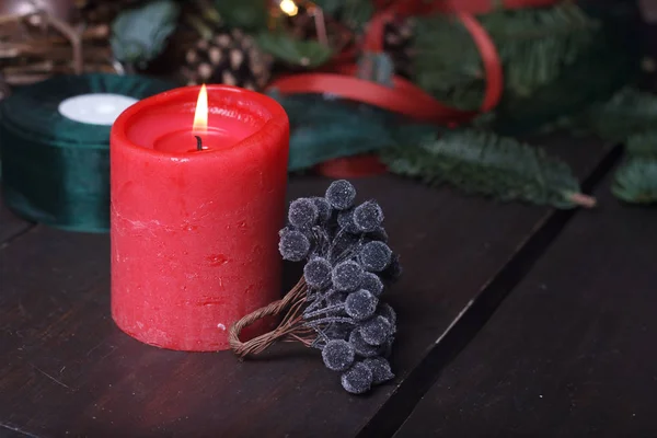 特写一个红色燃烧的蜡烛和人造黑色浆果作为圣诞花环，节日装饰，有选择的焦点 — 图库照片