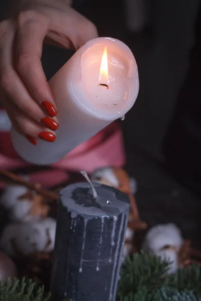 Nahaufnahme der Hand einer Frau, die geschmolzenes Wachs aus einer weißen Kerze auf schwarze Weihnachtskranzdekoration gießt, selektiver Fokus — Stockfoto