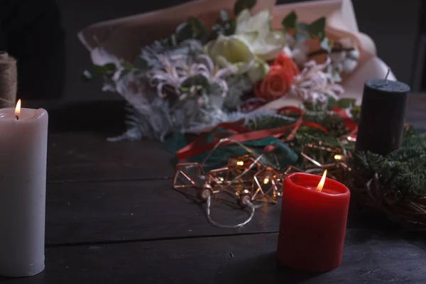 在制作圣诞花环的同时，用点燃的蜡烛在舒适的花店桌旁进行特写，有选择地聚焦 — 图库照片