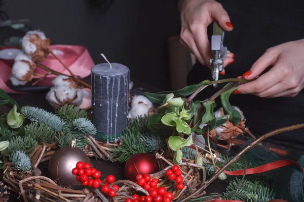 Close-up de uma florista feminina fazendo uma coroa de Natal de ramos de abeto, bolhas de Natal e decoração natural, foco seletivo — Fotografia de Stock