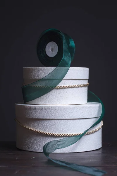 Κοντινό πλάνο δύο λευκών στρογγυλών καπέλων δώρο κουτιά και μια πράσινη κορδέλα σε σκούρο φόντο, επιλεκτική εστίαση — Φωτογραφία Αρχείου
